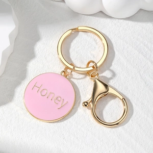 Detailed macro view of golden Honey letter heart keychain with pink enamel finish
