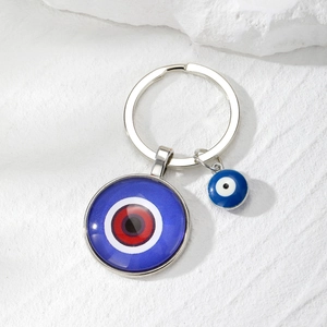 Detailed macro view of an Evil Eye keychain with glass cabochon on a stone surface