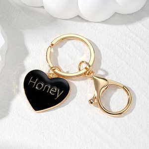 Macro view of gold keychain with black heart pendant featuring Honey lettering detail
