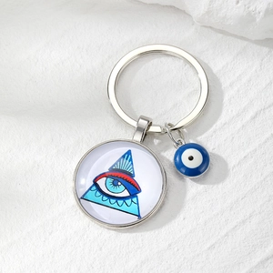 Macro detail of Evil Eye glass keychain with silver metal ring on white stone texture
