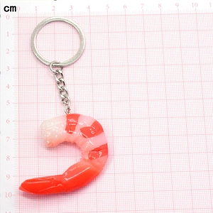 Detailed view of creative shrimp food pendant with silver keychain on pink grid paper