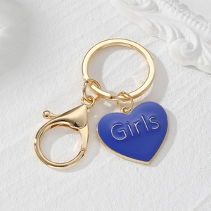 Detail of blue heart keychain with Girls text and golden lobster clasp on marble stone