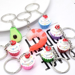 Detailed close-up of colorful avocado, shrimp, and cupcake food charms with keyrings