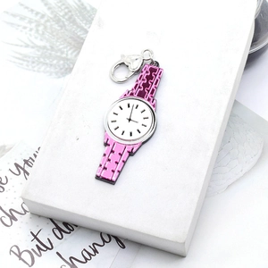Pink acrylic watch pendant keychain with a heart-shaped clasp on a white prop stand
