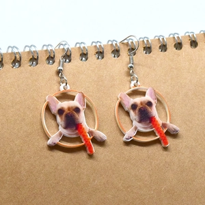 Dettaglio degli orecchini pendenti in acrilico con bulldog francese su carta kraft beige