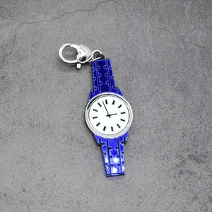 Detail of blue acrylic watch charm with heart lobster clasp on stone texture background