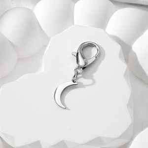 Polished silver crescent moon pendant with lobster clasp on a white heart stone base