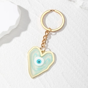 Macro detail of heart-shaped evil eye keychain with blue marble resin and gold frame