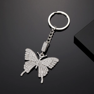 Elegante portachiavi a farfalla con strass bianchi brillanti su superficie metallica
