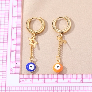 Gold evil eye earrings with cross chain and asymmetrical charms on a neutral fabric
