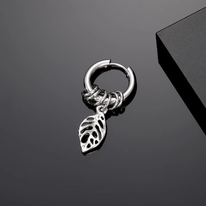 Macro detail of silver stainless steel hoop earring with hollow monstera leaf pendant