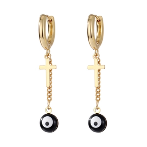 Macro shot of gold stainless steel earrings with cross pendant and evil eye bead