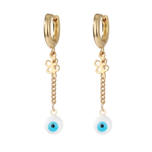 Detailed view of gold huggie earrings with cross chain and evil eye charms on white background