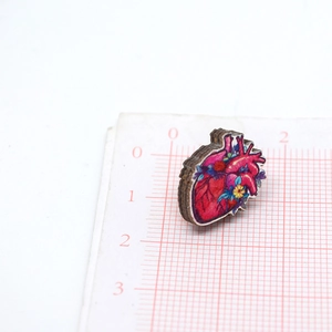 Vista macro de broche de madera con forma de corazón anatómico sobre papel milimetrado
