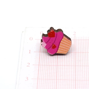 Detalle de pendiente de madera en forma de cupcake con crema rosa y corazones rojos