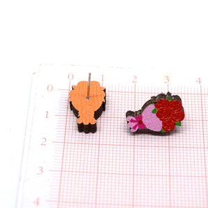 Vista de detalle de pendientes de madera con rosas rojas y pernos sobre tarjeta de escala