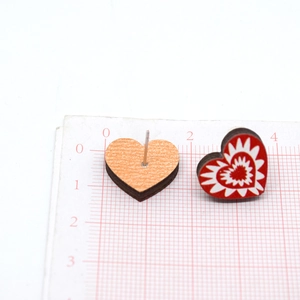 Detalle de pendientes de madera en forma de corazón con diseño rojo y textura de madera