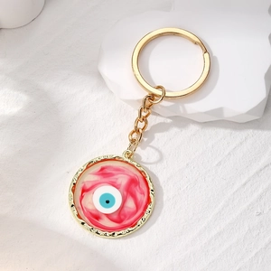 Artistic evil eye keychain with red and white resin smudge pattern in gold hardware