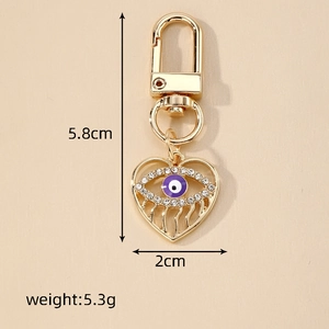 Golden heart-shaped evil eye keychain with purple rhinestones and D-ring swivel clasp