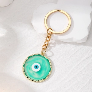 Detailed close-up of golden Evil Eye keychain with marbled blue resin and textured edges