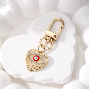 Golden heart evil eye keychain with sparkling crystals and red enamel on stone prop