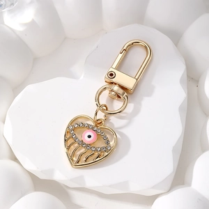 Gold hollow heart keychain with pink evil eye and sparkling rhinestones on stone tray