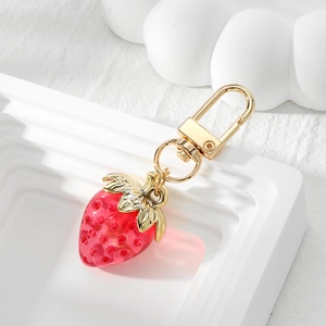Detail eines roten Erdbeeren Schlüsselanhängers aus Harz mit goldenem Blatt und Clip