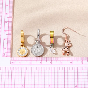 Stainless steel earring set with giraffe charm and coin pendant shown with measurement ruler