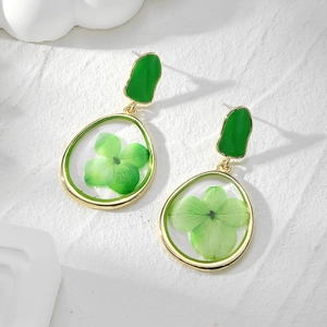 Detail view of teardrop earrings with real green dried flowers in golden metal frame