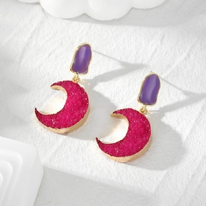 Detailed view of bohemian gold earrings with purple resin and rose red crescent charms