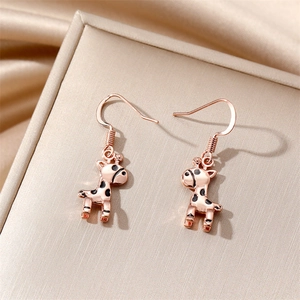 Rose gold giraffe drop earrings with black enamel spots on a silk jewelry box