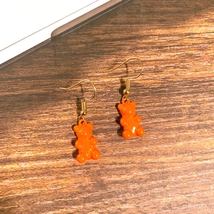 Detailansicht der leuchtend orangefarbenen Gummibärchen-Ohrhänger mit Goldhaken