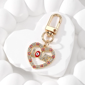 Detailed view of a gold LOVE heart keychain with crystal rhinestones and blue evil eye charms
