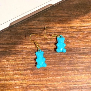 Detailaufnahme blauer Bärenohrringe mit goldenen Metallhaken auf einer Holzoberfläche