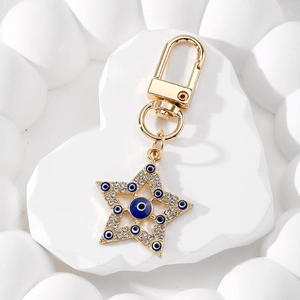 Detailed macro view of golden star Evil Eye keychain with sparkling blue rhinestones