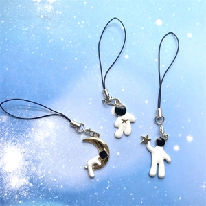 Close-up of cute cartoon astronaut phone charms with white enamel and golden stars
