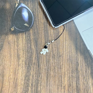 Cartoon astronaut phone charm with gold stars on dark wooden desk background