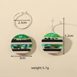 Detailed view of geometric earrings featuring green resin and natural wood stripe patterns