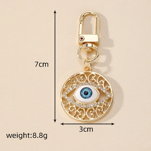 Detail of evil eye keychain showing dimensions 7x3cm and weight 8.8g in gold finish