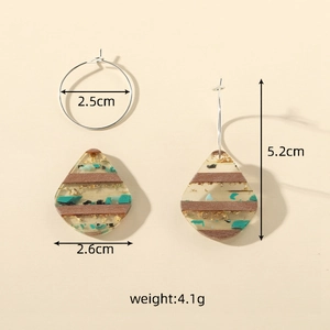 Detail view of teardrop earrings with wood texture, turquoise stones and gold foil flakes