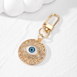 Detailed macro of gold alloy evil eye keychain with blue resin eye and small crystals