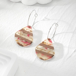 Waterdrop resin earrings with gold foil and pink patterns on textured white background