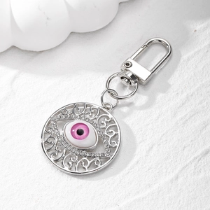 Close-up of pink devil's eye keychain with hollow vintage pattern and crystal rhinestones