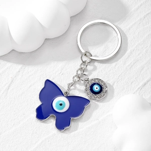 Porte-clés papillon œil bleu avec breloque en strass brillants sur un fond blanc épuré