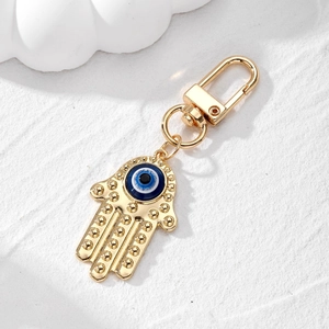 Detailed close-up of gold Hamsa hand keychain featuring the blue Evil Eye charm