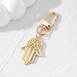 Golden Hamsa Hand keychain with blue evil eye pendant on a white marble background