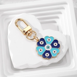 Detailed close-up of blue floral evil eye keychain with gold lobster clasp on white stone