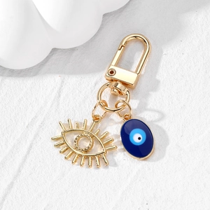 Porte-clés œil protecteur doré avec pendentif cils et émail bleu sur support en pierre