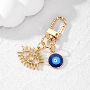 Porte-clés œil ajouré avec pendentif mauvais œil bleu sur fond blanc texturé