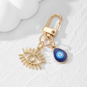 Détail de l'oeil doré à cils et du pendentif bleu mauvais oeil sur porte-clés doré